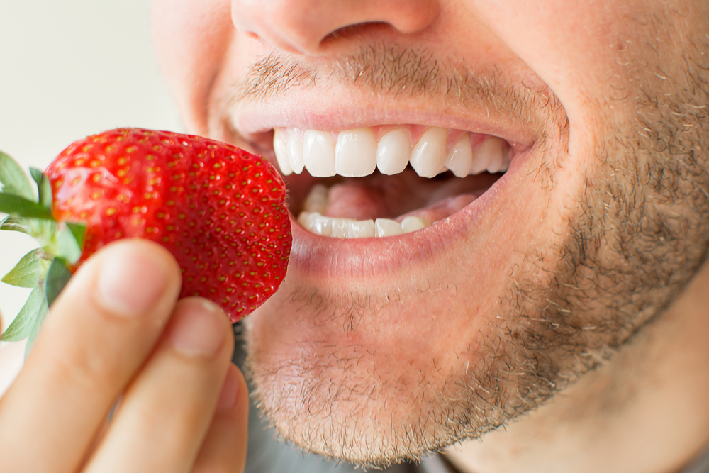 Man eating a strawberry one of the best foods for gum health