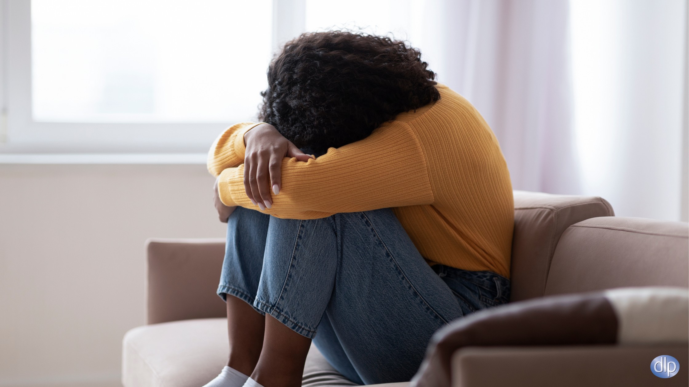 Woman sitting with head on knees, appearing emotionally distressed