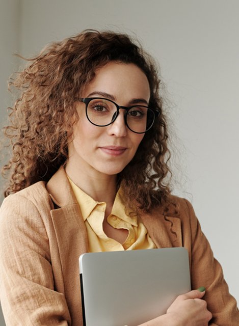 Woman wearing glasses holds her cheek in pain, appearing to suffer from a toothache.