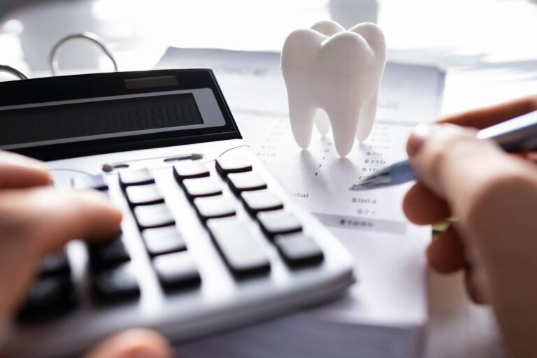 A pair of hands using a calculator and pen working out calculations on a dental claim