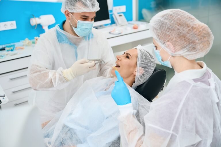 Female patient in a dentists chair with a dentist and a dental assistant performing a root canal