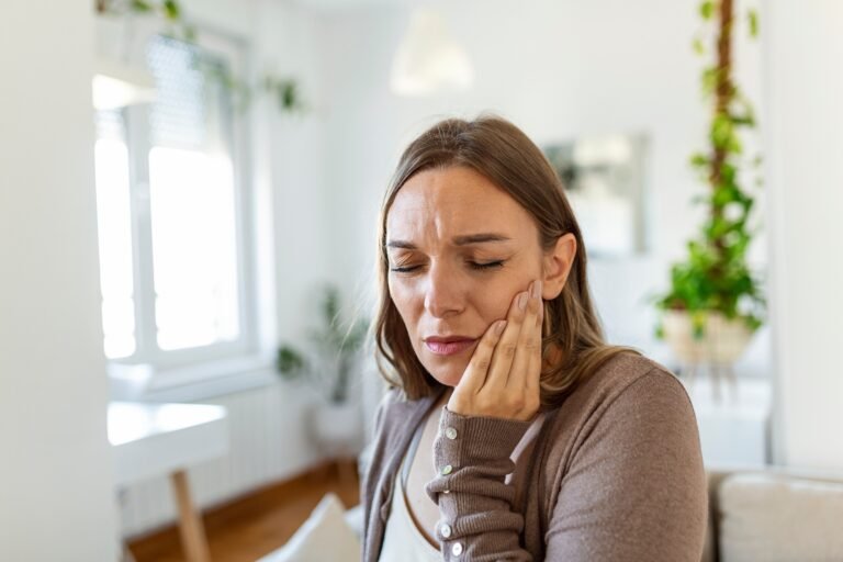 woman holding her jaw and wincing due to jaw pain after dental work.